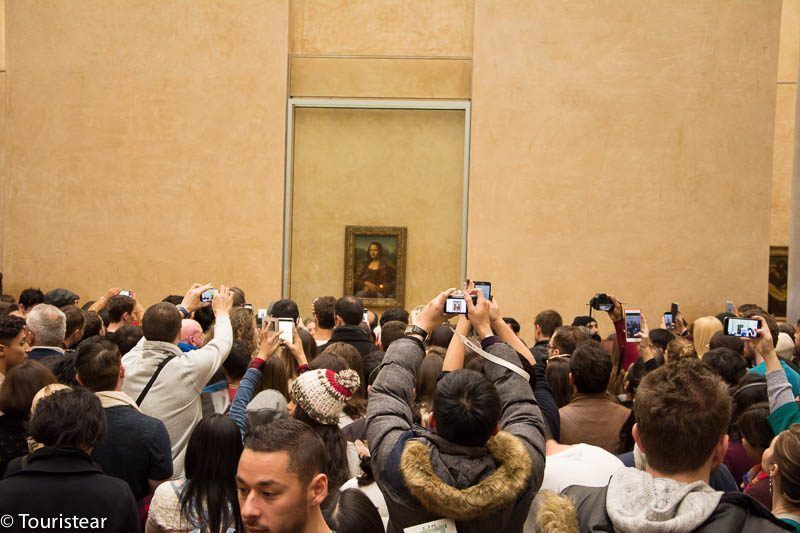 a pack of people taking a photo of the Monalisa during London Paris vacation 