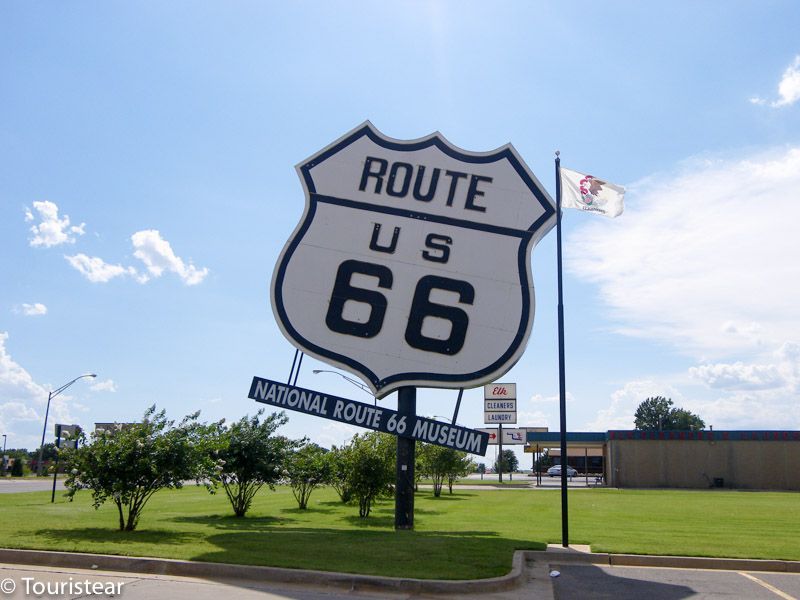 Ruta US 66 frente al Museo Nacional de la Ruta 66 bajo un cielo azul brillante y nubes blancas