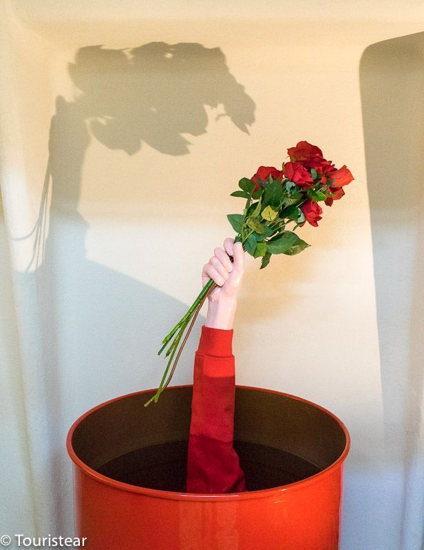Art at Casa Batllo, an arm with bouquet of red roses coming out of a red barrel, like moving around Barcelona