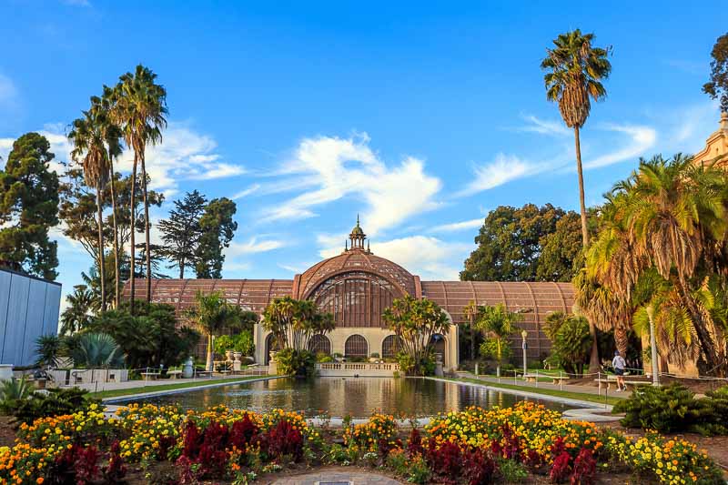 a green house surrounded by palm trees and flowers