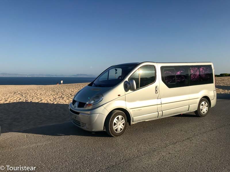 Grey-silver traffic camper van with the beach and blue sky