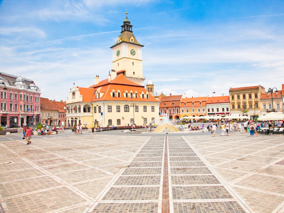 People hanging out and sitting down at the Council Square of Brasov during day time