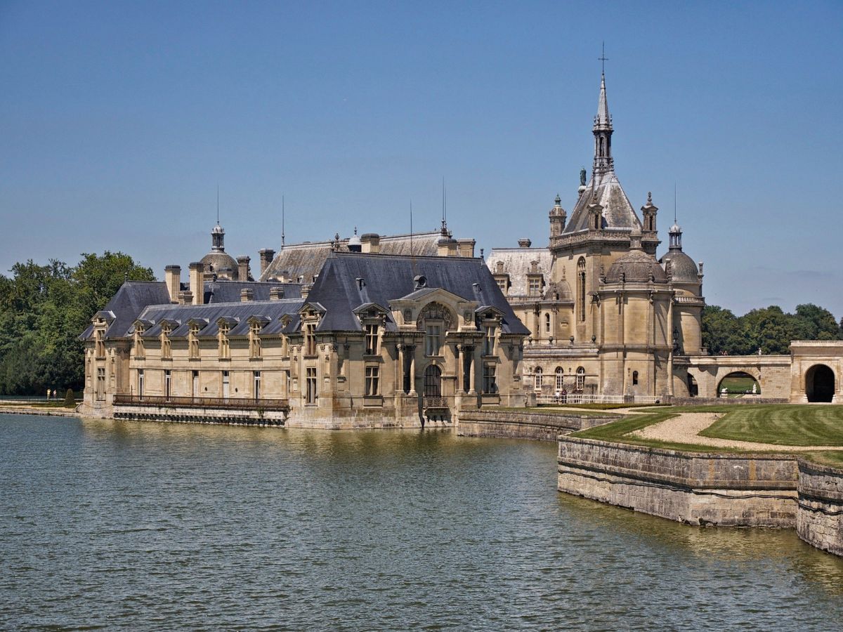 Chateau de Chantilly surrounded by water under clear skies in day trip from Paris