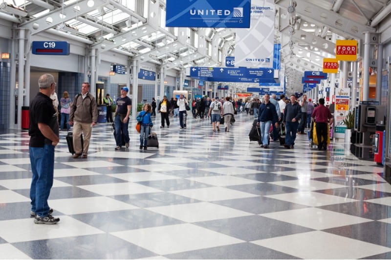 Aeropuerto Internacional O Hare con gente caminando y algunos buscando el mostrador de alquiler de coches en Chicago