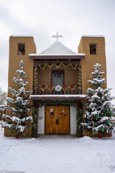 St. Francis of Assisi Church with snow and two Christmas trees.