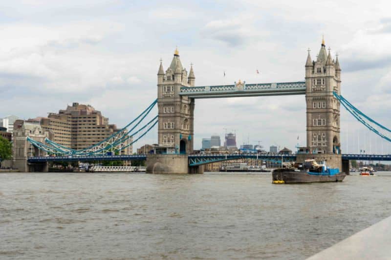 río con un puente, barcos y edificios al fondo uno de los destinos para su itinerario de vacaciones Londres París