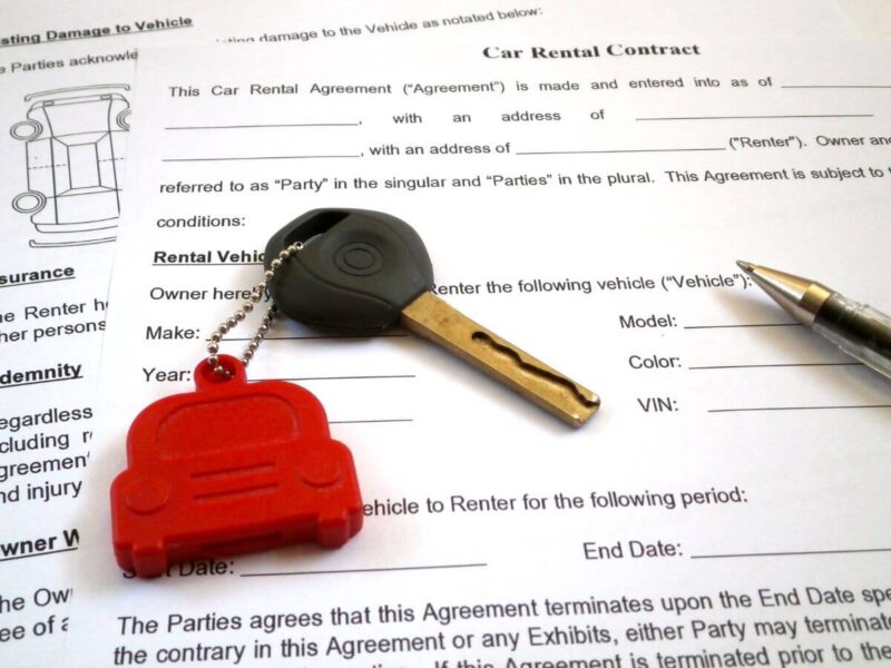 A sample car rental contract wiht pens and car keys on top of it in Chicago