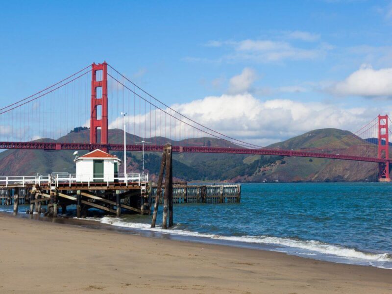 Bay Area shore with board walk and a bridge and mountains in the background, some of the road trip destinations in the usa
