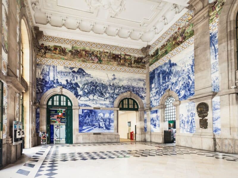 Inside the Sao Bento train station filled with blue frescos on tiles for a stopover to a drive from Lisbon to Porto