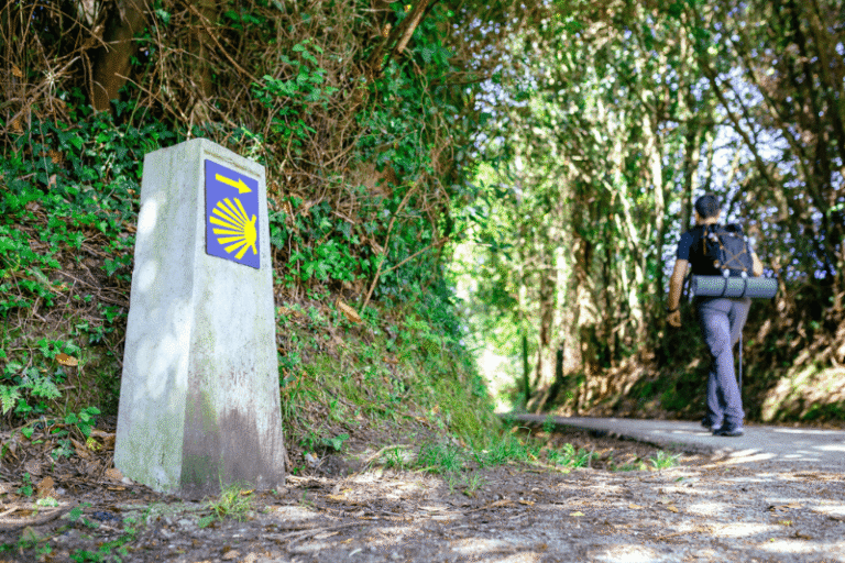 señal del camino de Santiago con peregrino caminando