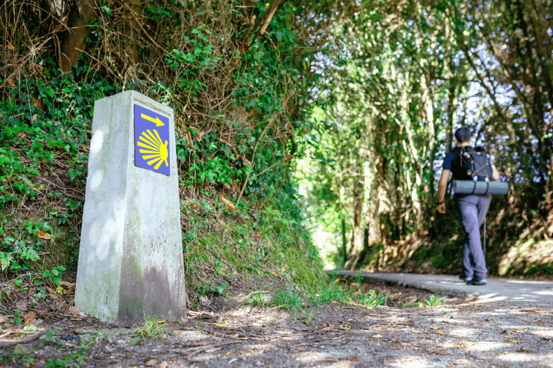 señal del camino de Santiago con peregrino caminando